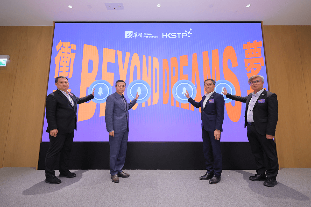 Four men in formal suits stand on a stage, each touching a circular icon, with a large digital display behind them featuring the words "BEYOND PEAK" and logos of China Resources and HKSTP, indicating a collaboration to boost startup talent and innovation in AI and biomedicine in Hong Kong.