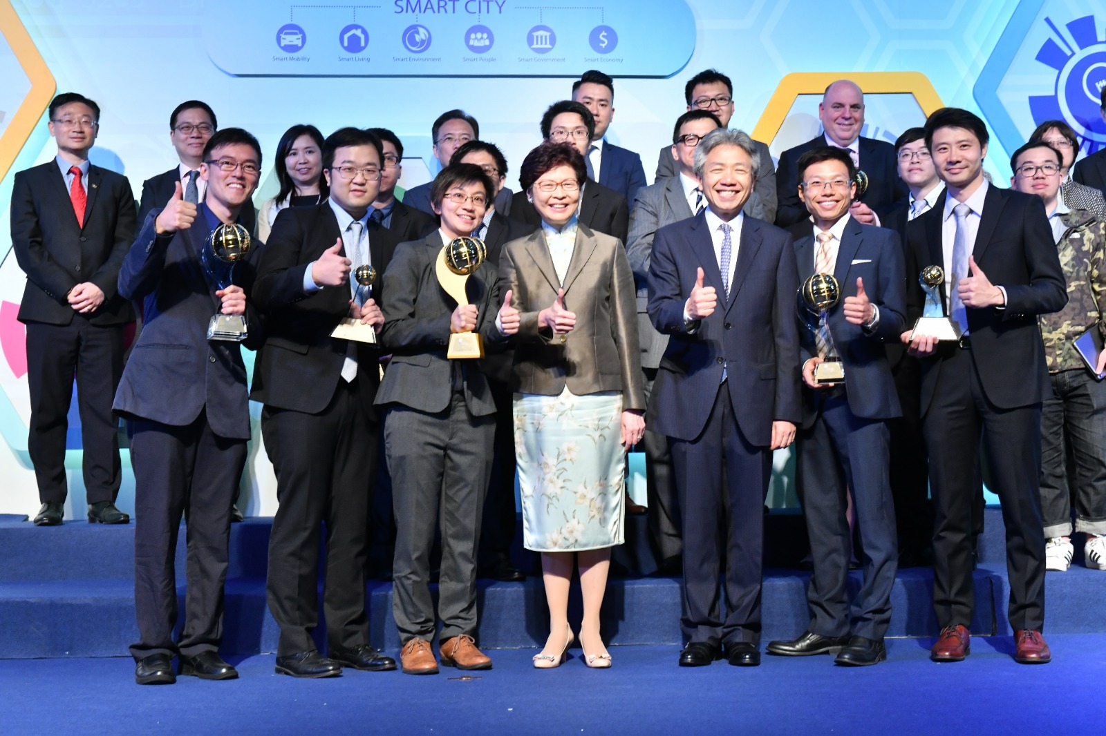 在「2018 香港資訊及通訊科技獎」頒奬典禮上，香港特別行政區行政長官林鄭月娥頒發「全年大獎」予倍靈科技有限公司總裁梁立慧博士(前排左三)。